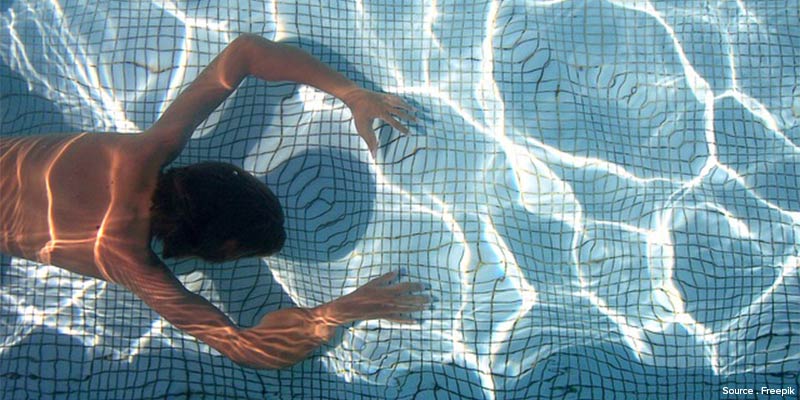 Homme nageant dans une piscine